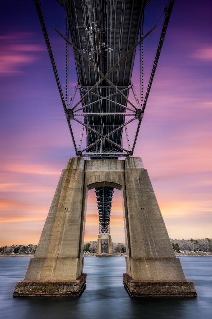 A bridge over a body of water with a sunset in the background.