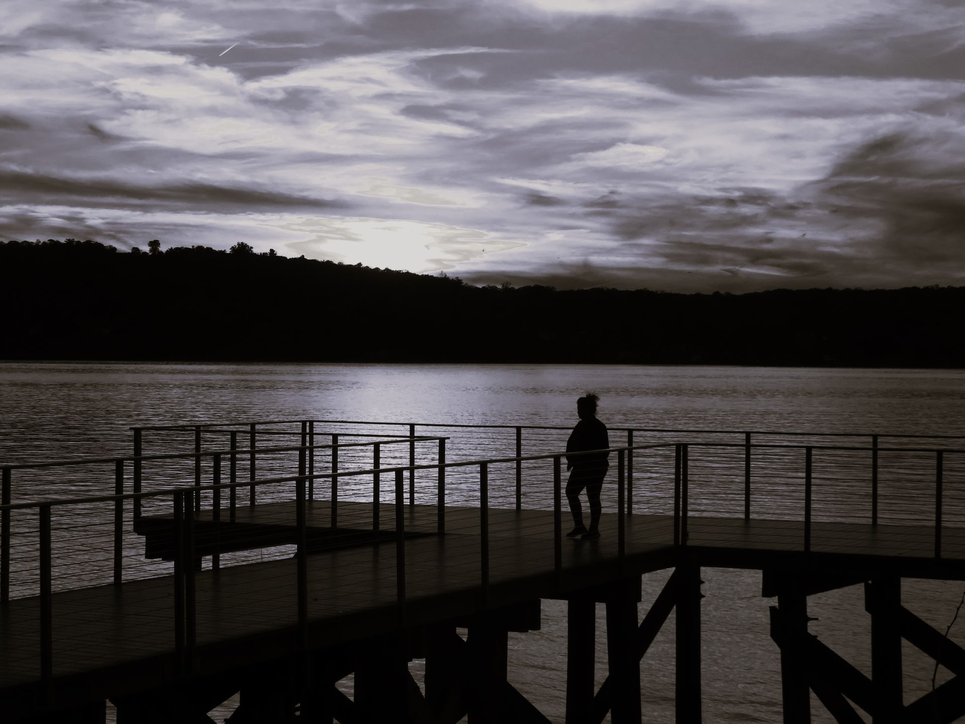 A person is standing on a dock overlooking a lake