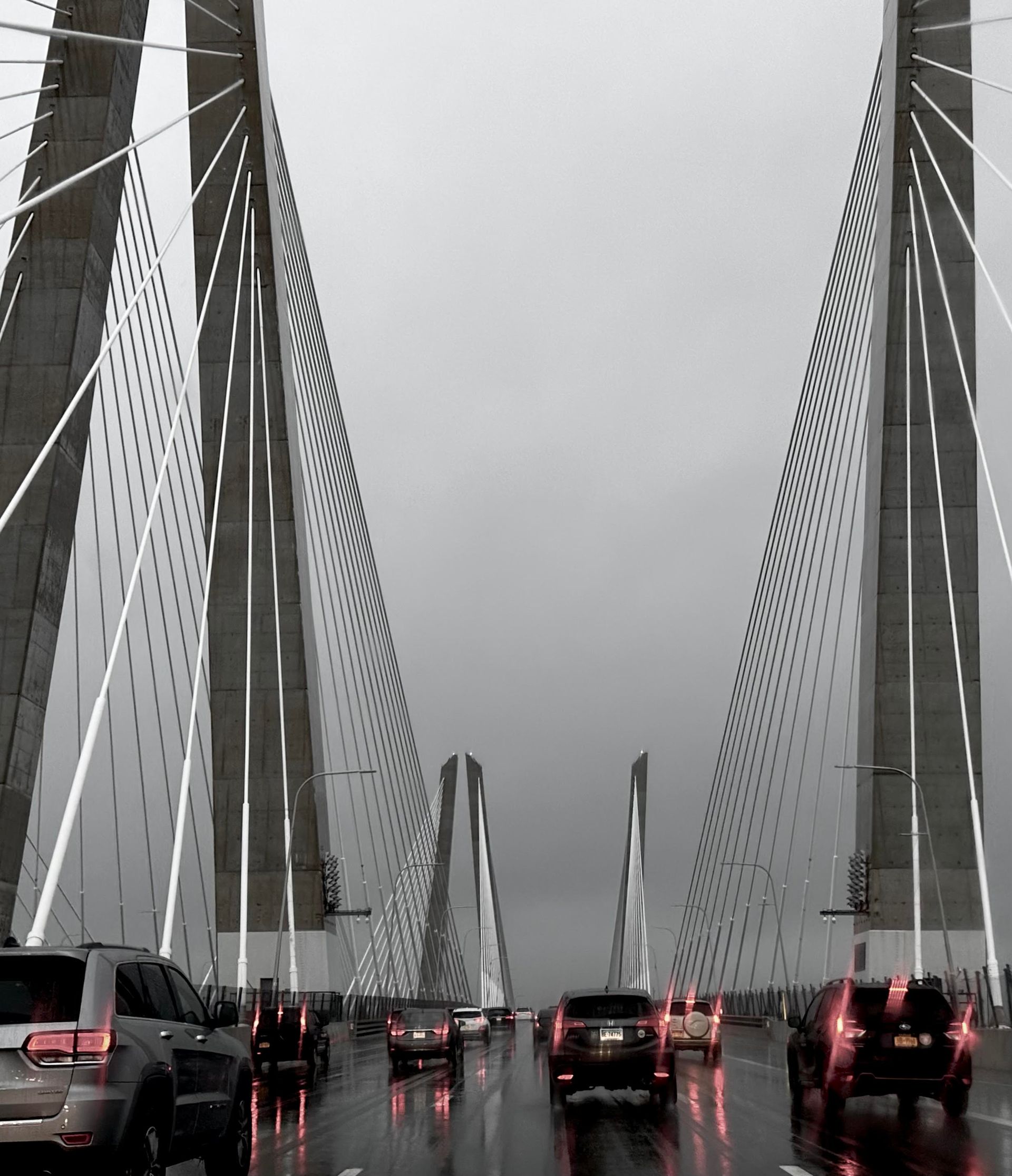 A black and white photo of cars driving on a bridge