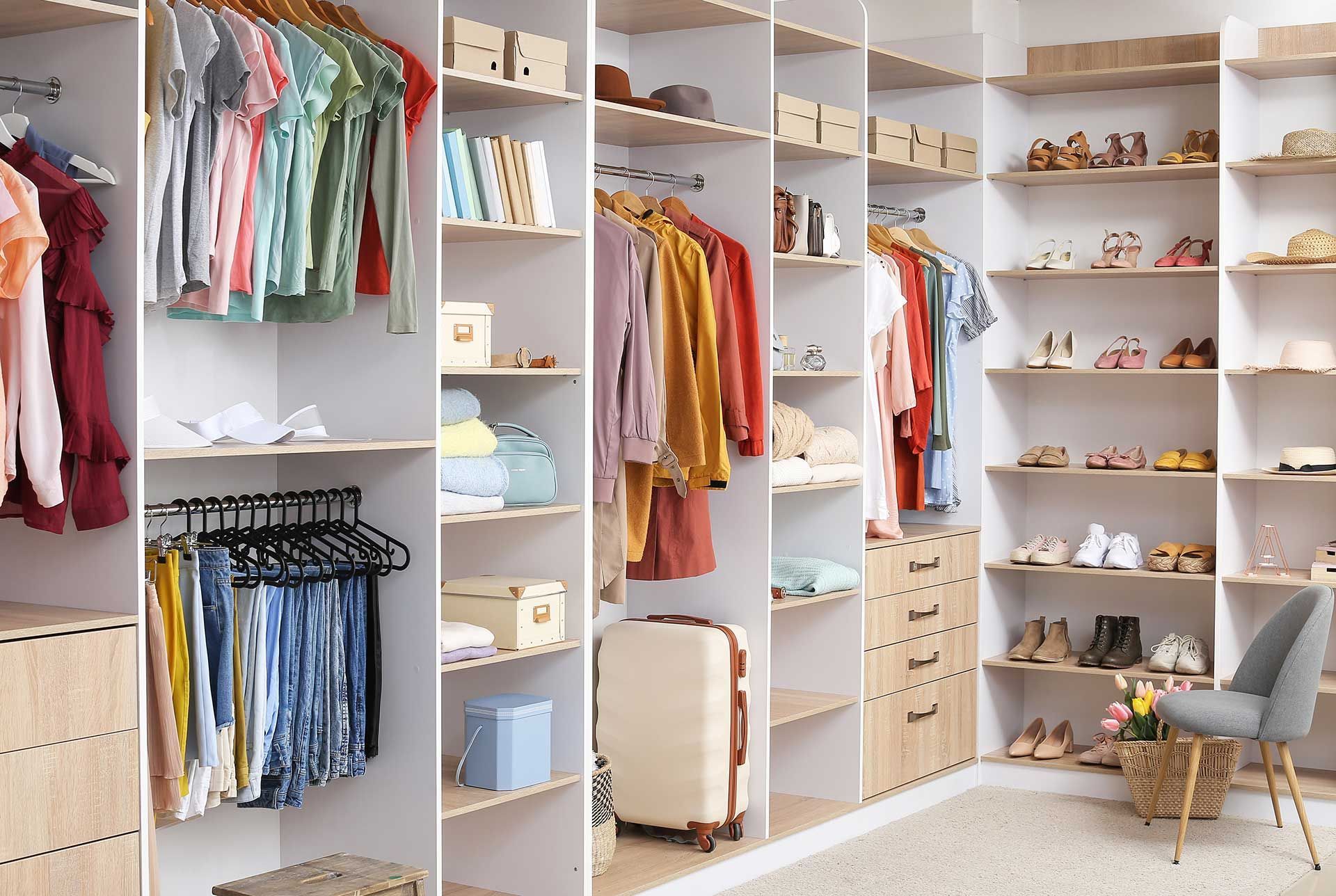 Walk-in closet with clothes hanging, shelves with shoes and storage boxes.