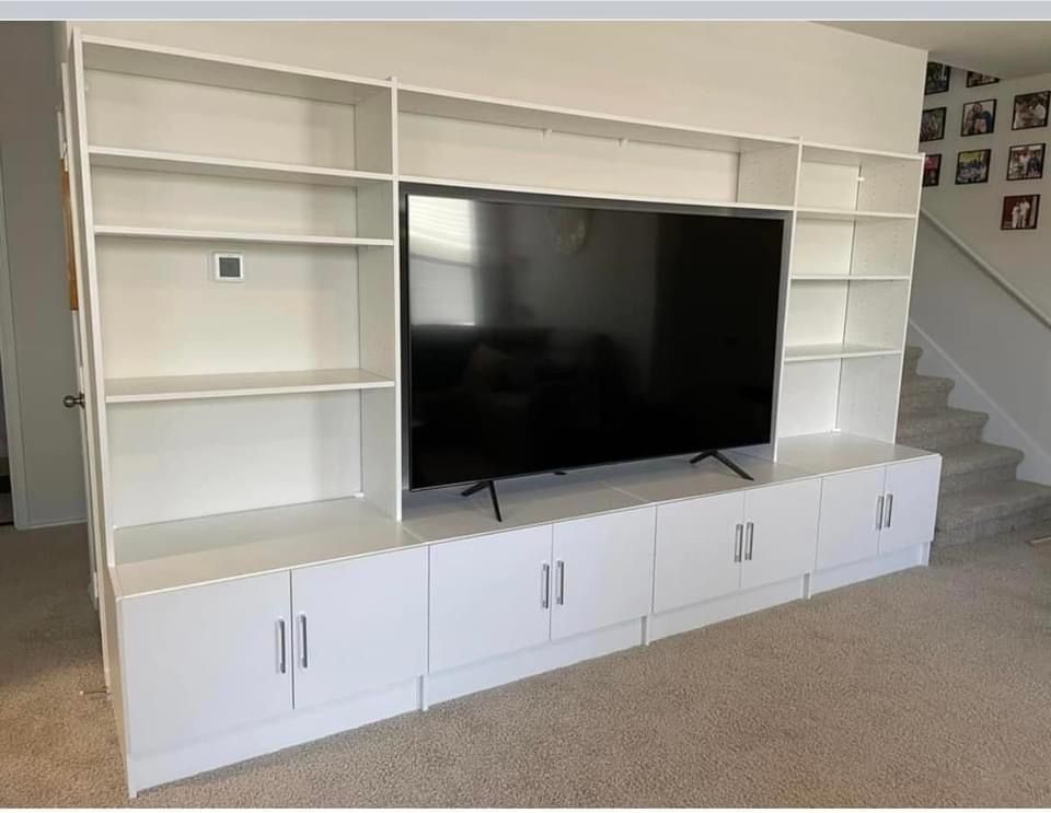 White built-in entertainment center with shelves, cabinets, and a large black television.