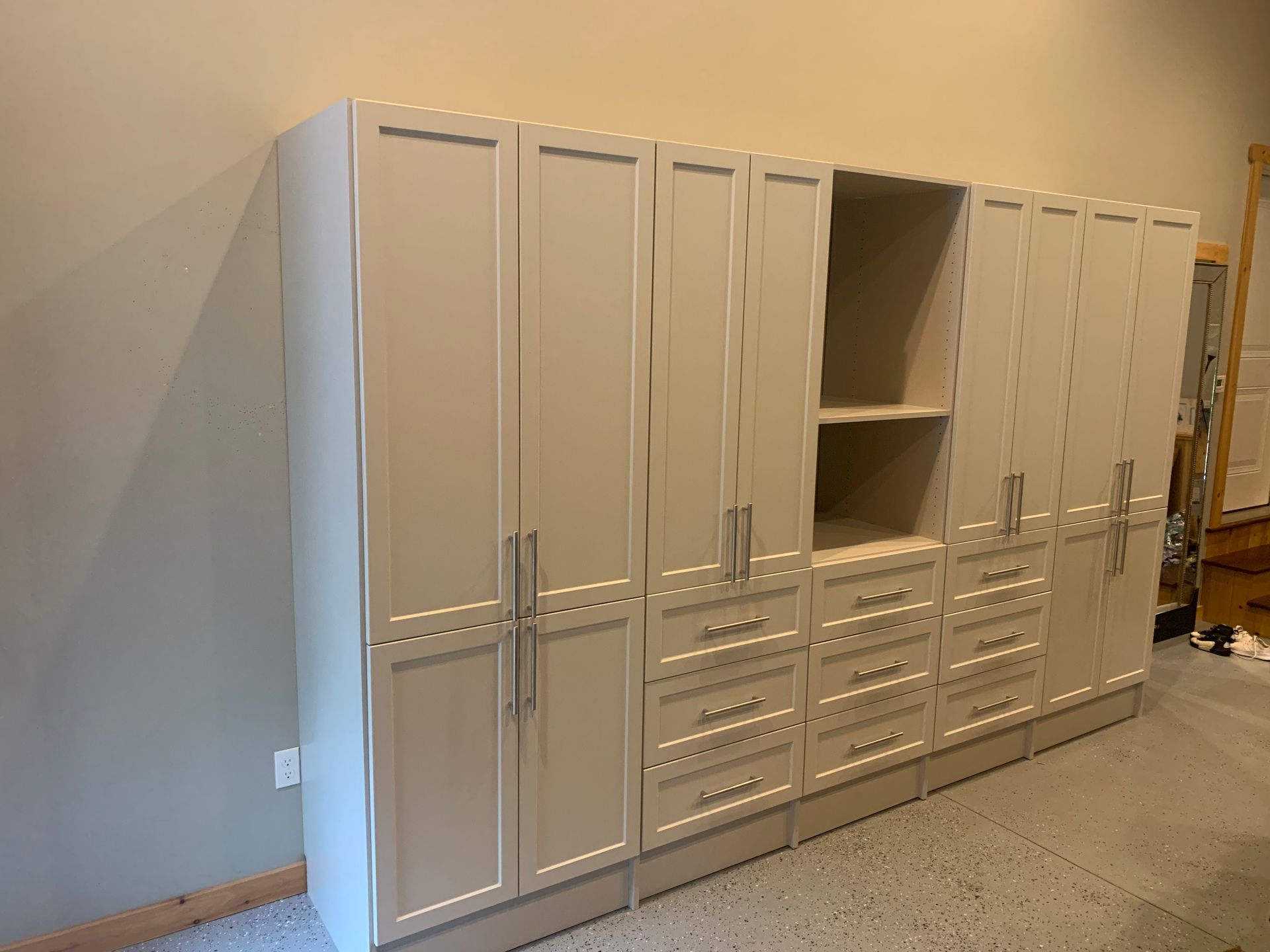 Light beige cabinets with drawers and tall doors in a garage setting.