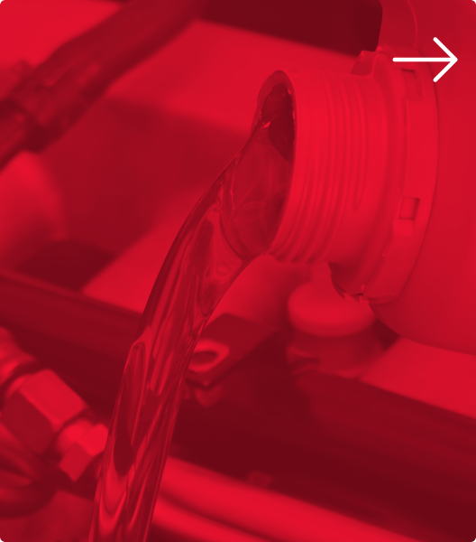 A close-up of dark fluid pouring from a plastic spout into a machine or reservoir | Euro Auto Tech & Smog