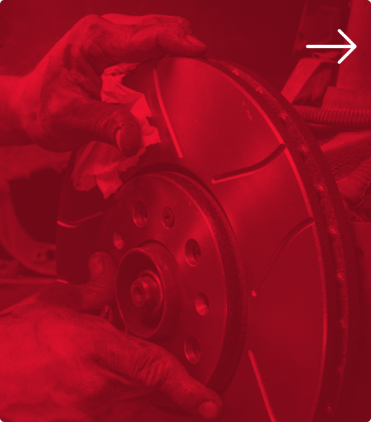 Hands installing a vented disc brake rotor onto a vehicle, a white arrow in the corner pointing right | Euro Auto Tech & Smog