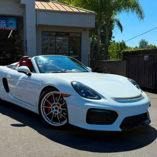 A white Porsche Boxster Spyder convertible parked in a sunny outdoor setting in front of a building | Euro Auto Tech & Smog