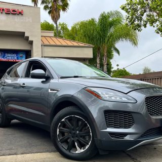 A grey Jaguar E-Pace SUV parked in front of a building with a 
