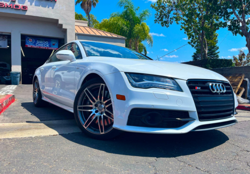 A red Audi sedan parked outside of an automotive repair shop with a Smog Check sign in the background | Euro Auto Tech & Smog