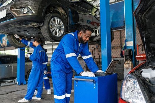 Technicians working inside the garage, with a black car on the lift | Euro Auto Tech & Smog