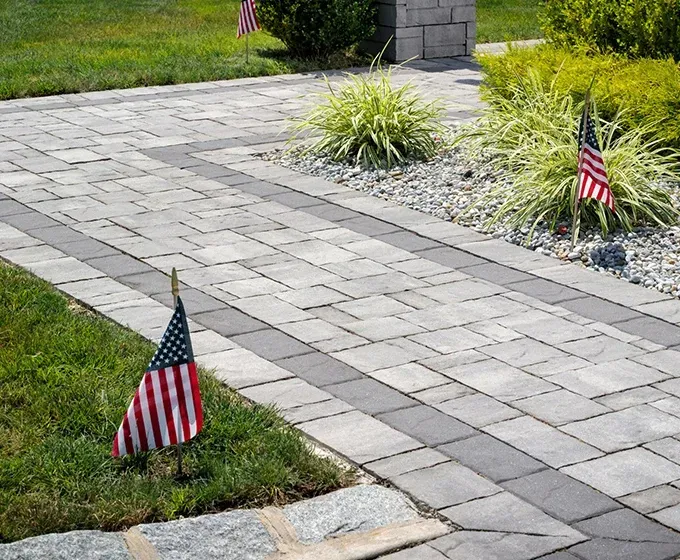 Two small american flags are sitting on a brick walkway.