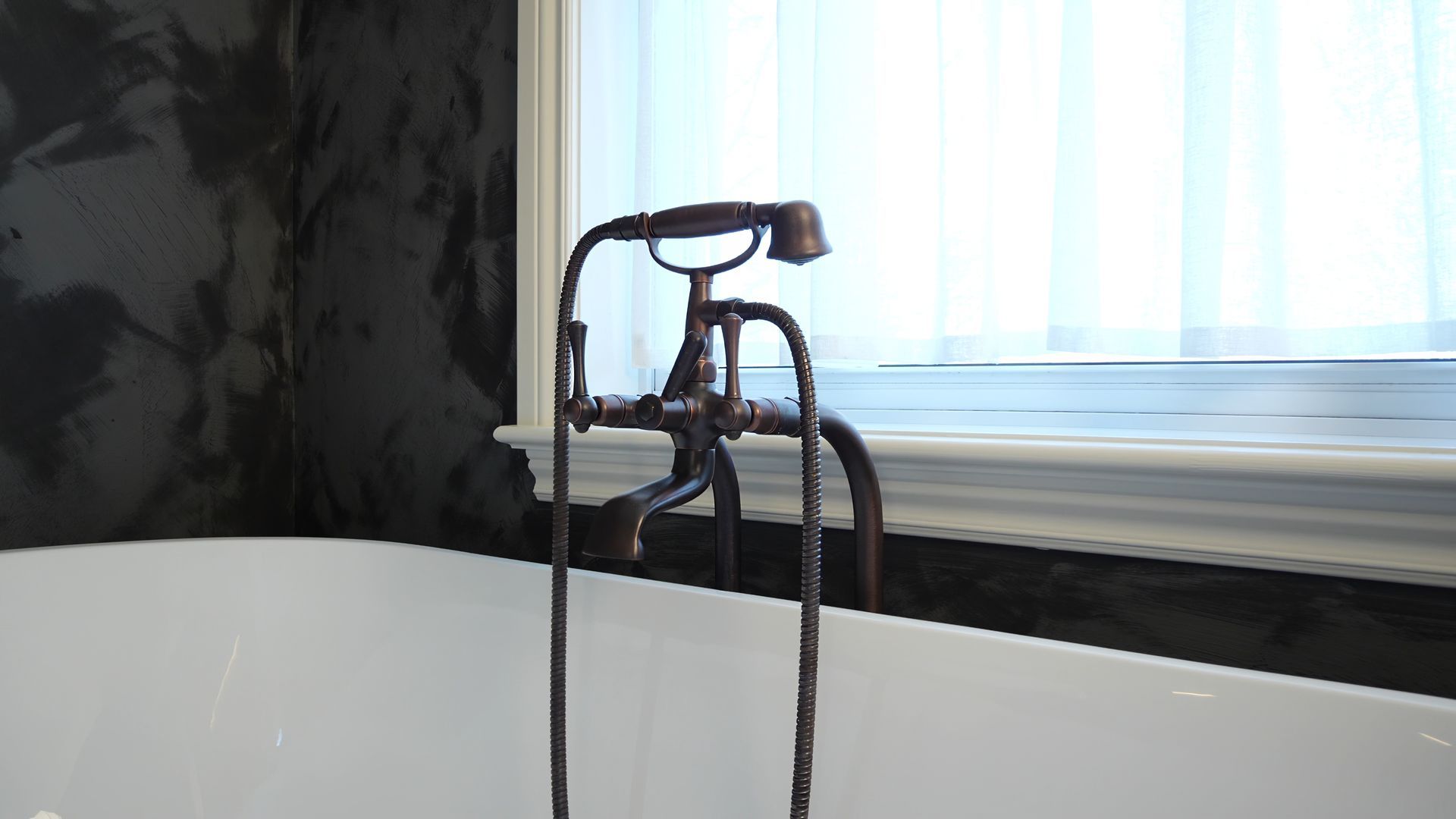 Une baignoire avec un robinet attaché et une fenêtre en arrière-plan.