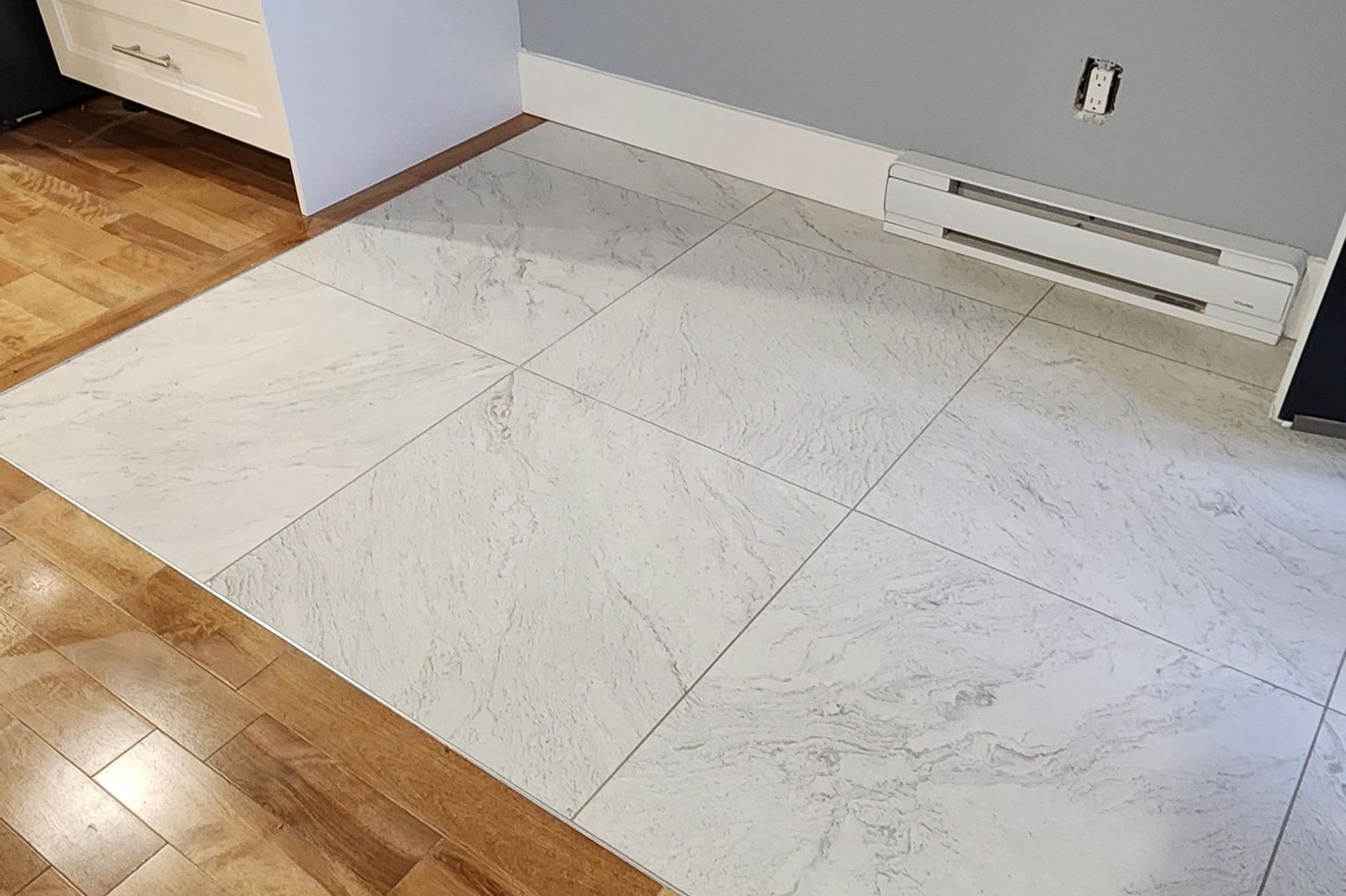 A white tile floor with a wooden floor in a room.