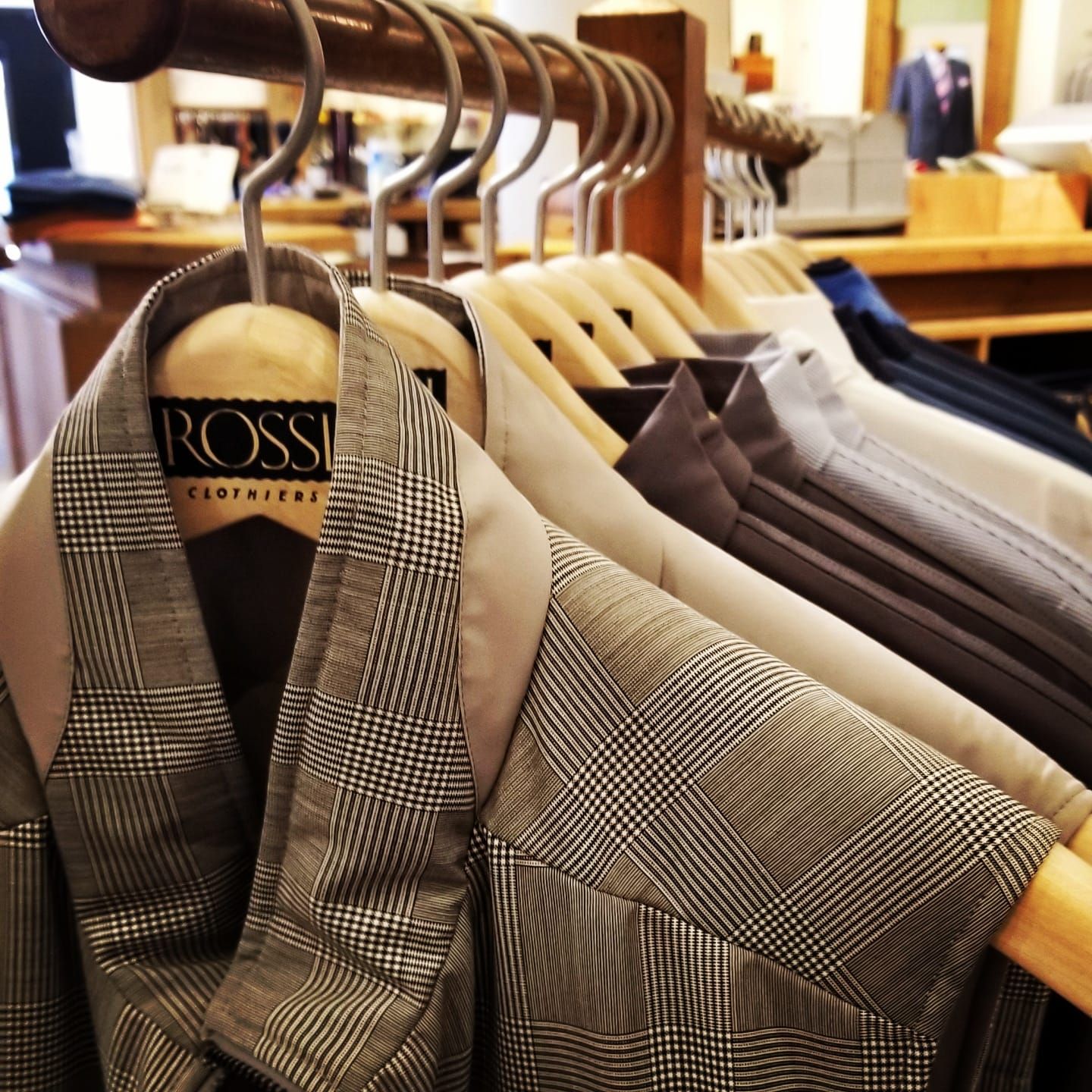 A photo of various suit jackets on a clothing rack. Displaying the vast variety Rossi has to offer.