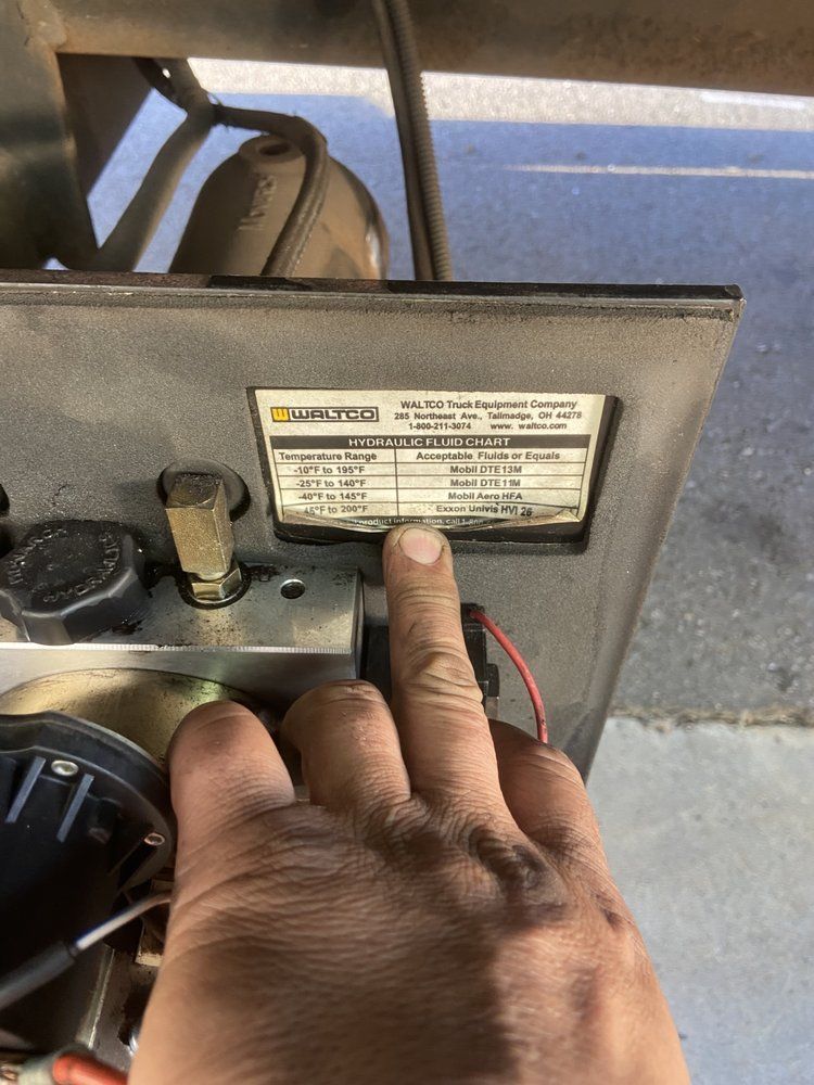 Hand pointing at a metal plate with technical specifications on a machine, likely a compressor.