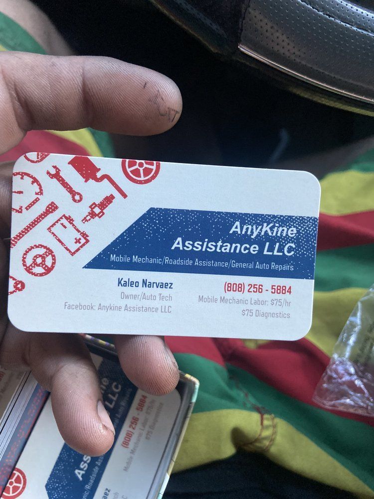 Person holding AnyKine Assistance LLC business cards with white, blue, and red graphics, and contact info.