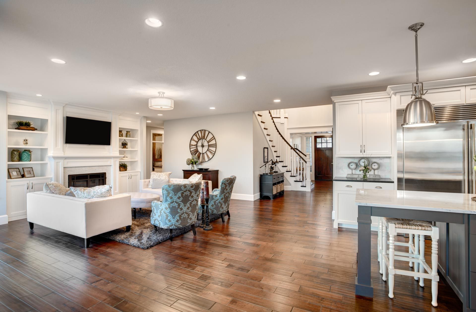A living room and kitchen in a new home with hardwood floors and stainless steel appliances.