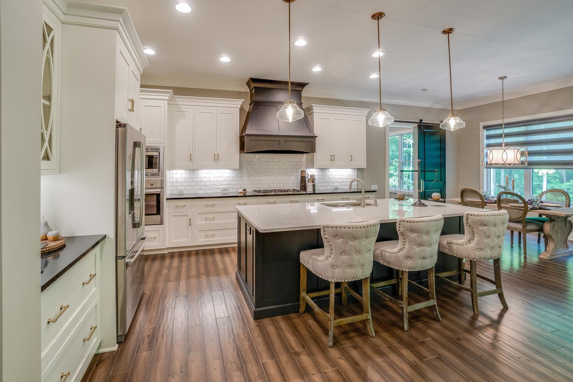 A kitchen with white cabinets , stainless steel appliances , and a large island.