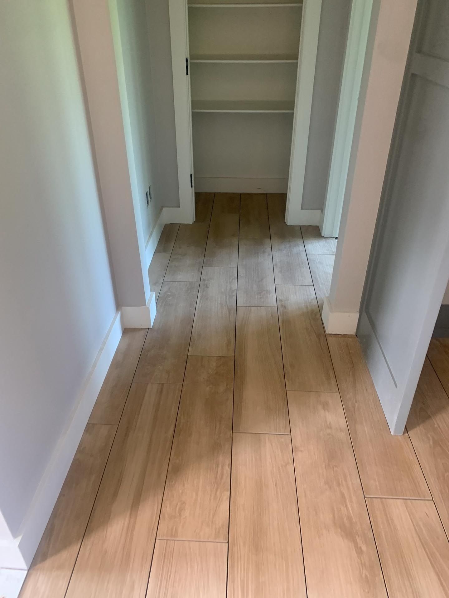 A hallway with wooden floors and shelves in a house.