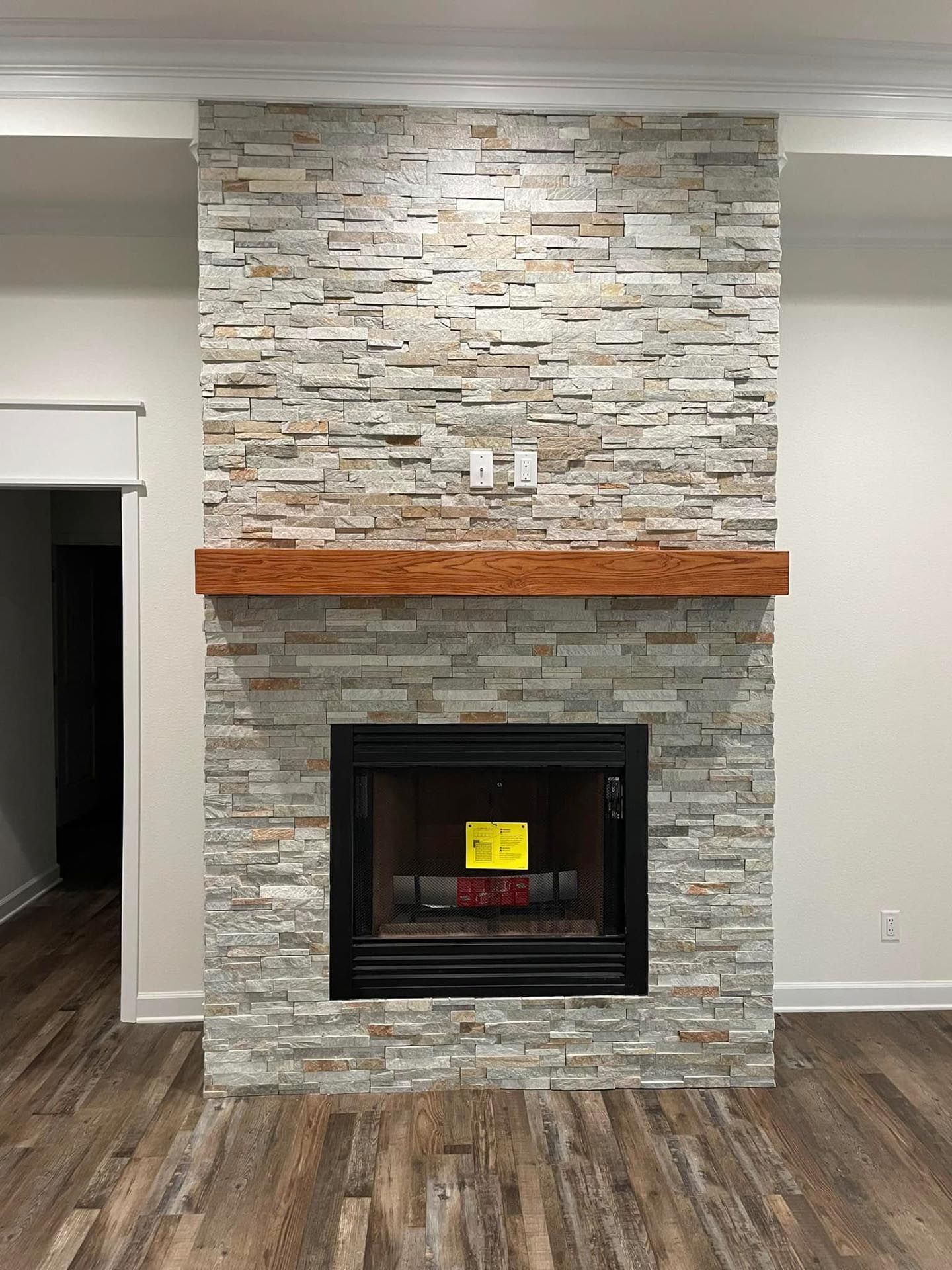A living room with a fireplace and a wooden mantle.