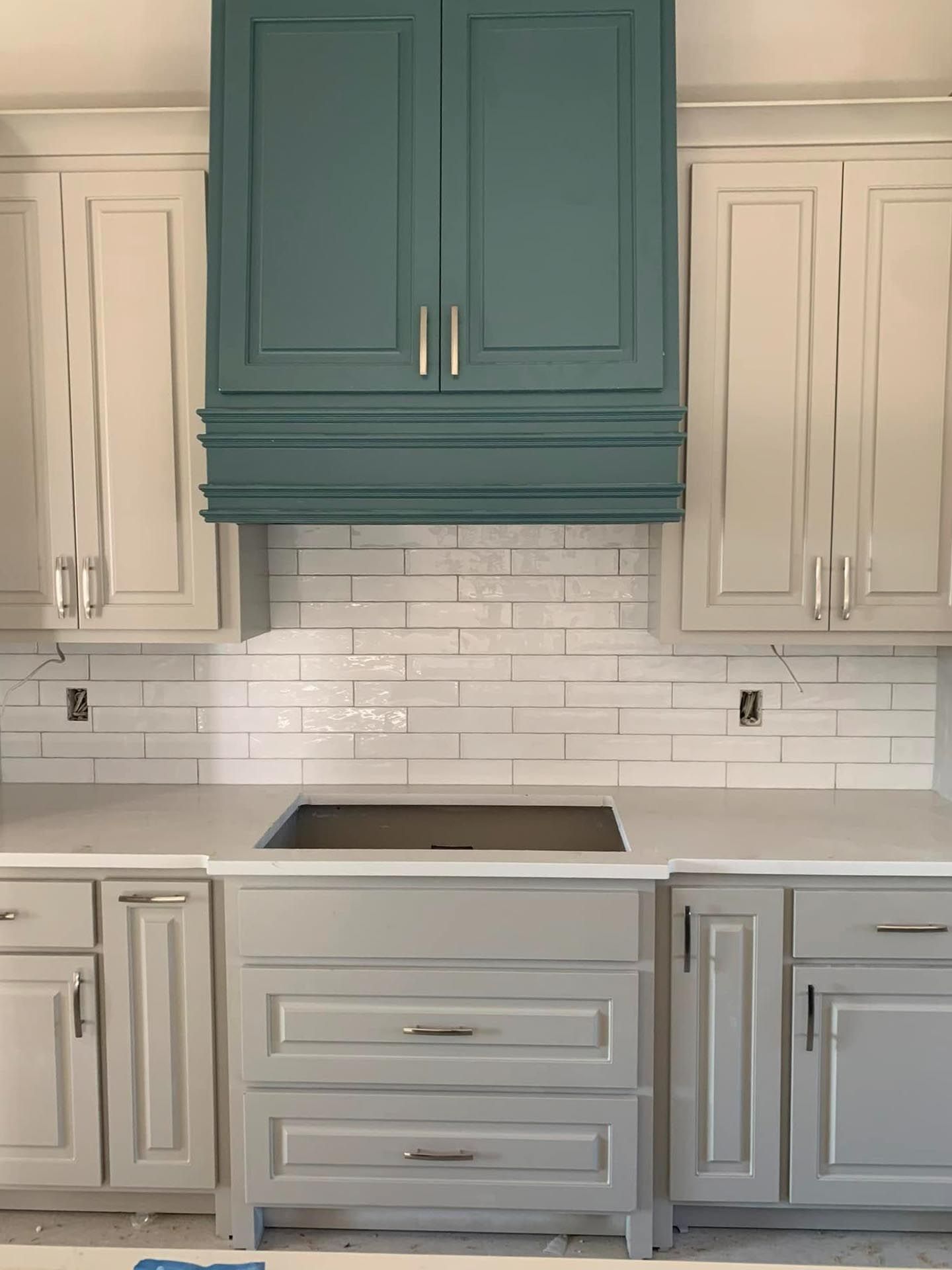 A kitchen with white cabinets and green cabinets and a stove top oven.