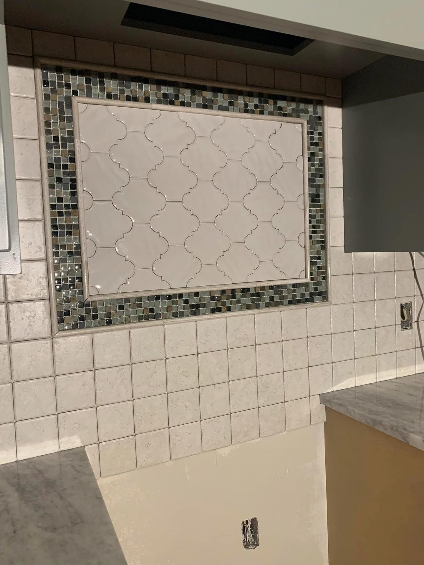 A kitchen with white tiles and a picture on the wall