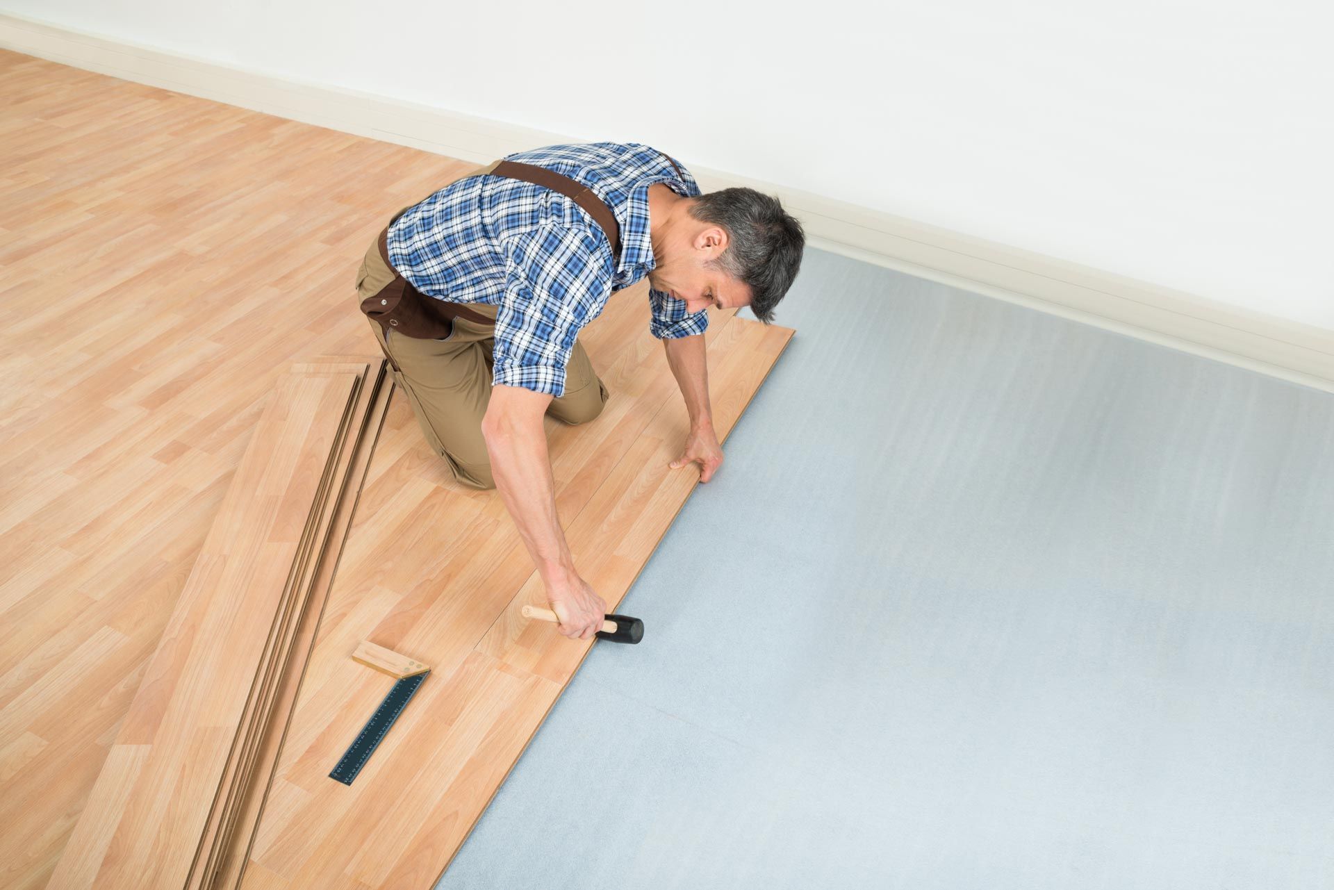 A man is installing a wooden floor in a room.