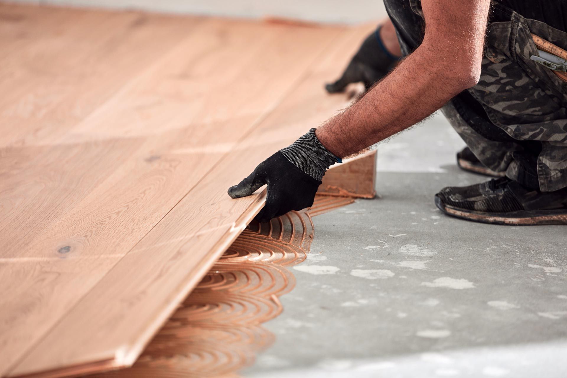 A man is installing a wooden floor in a room.