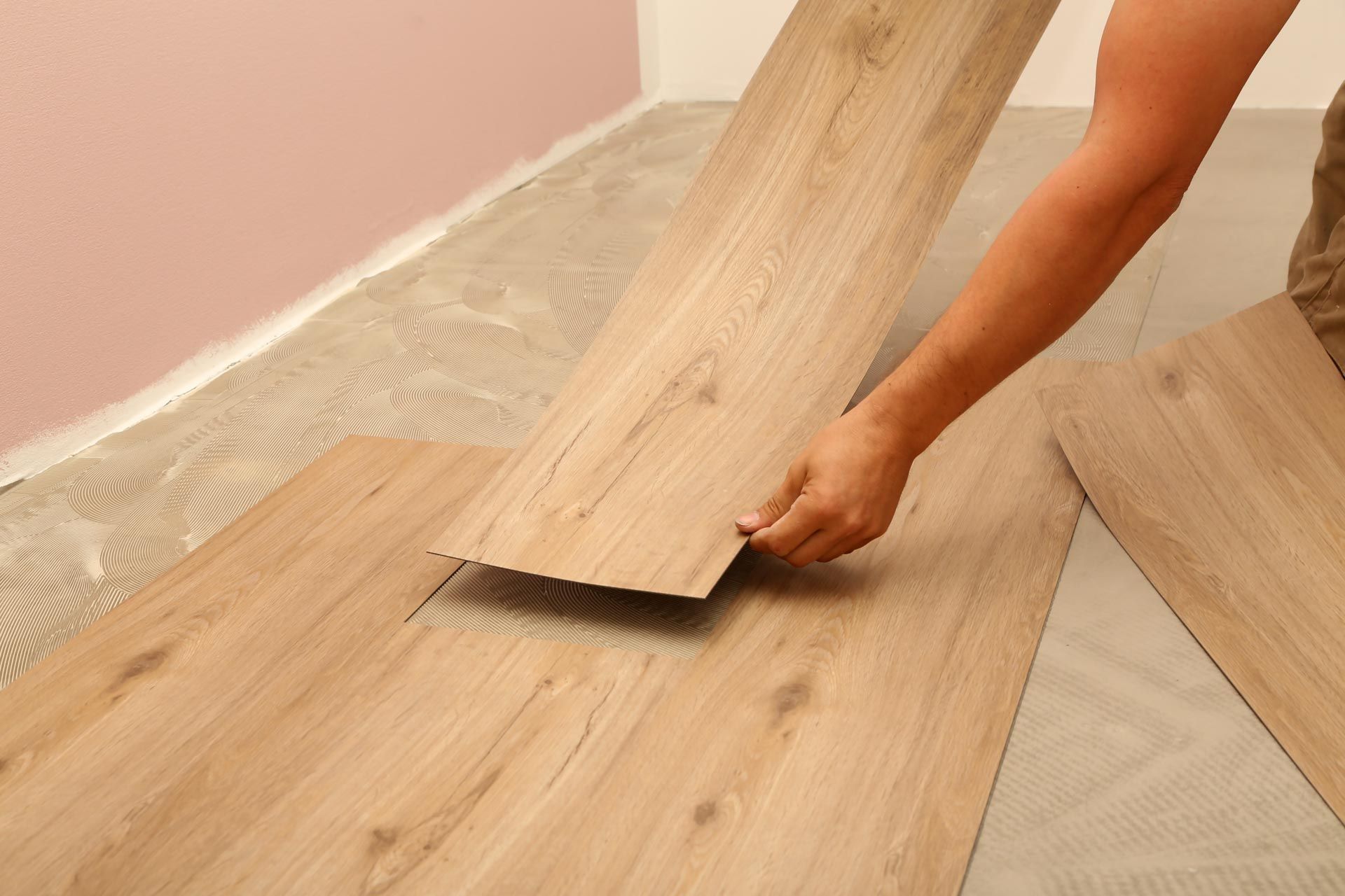 A person is installing a wooden floor in a room.