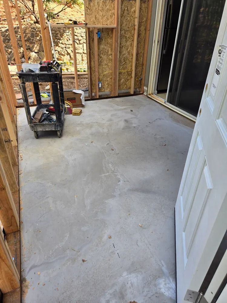 Unfinished room with concrete floor, exposed framing, and a sliding glass door opening to an outdoor deck.