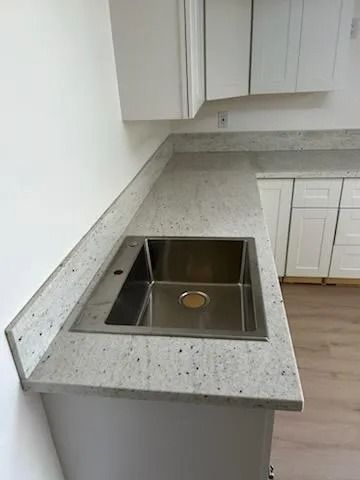 Modern kitchen countertop with a stainless steel sink and light speckled granite surface.