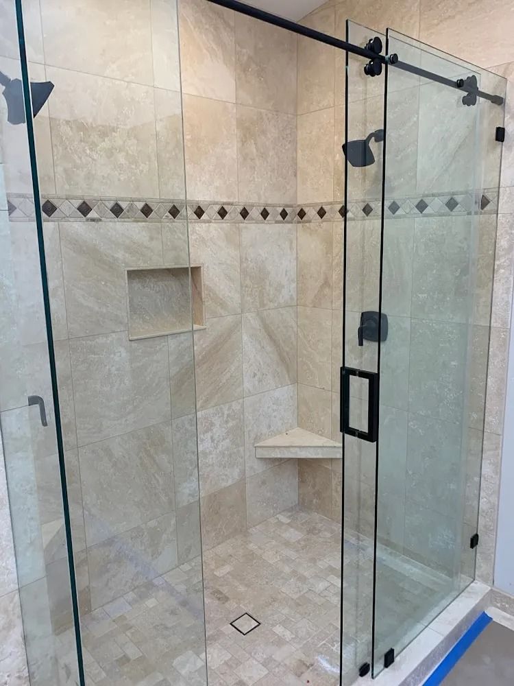 Glass-enclosed tiled shower with built-in niches, bench, and decorative border trim