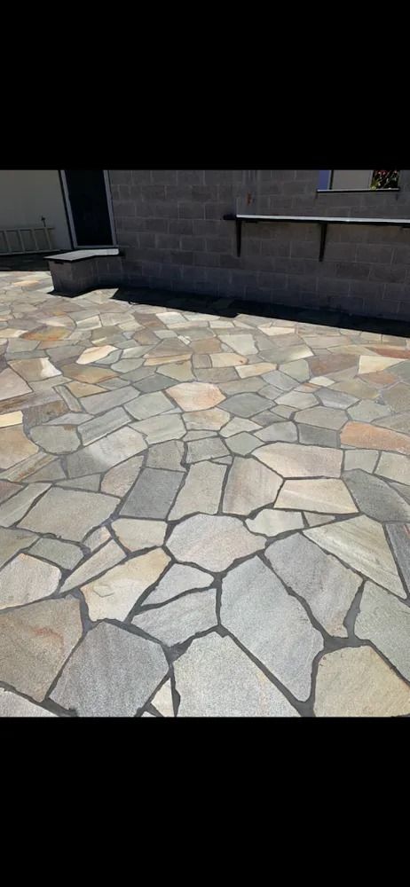 Stone-paved patio beside a dark building wall in bright daylight