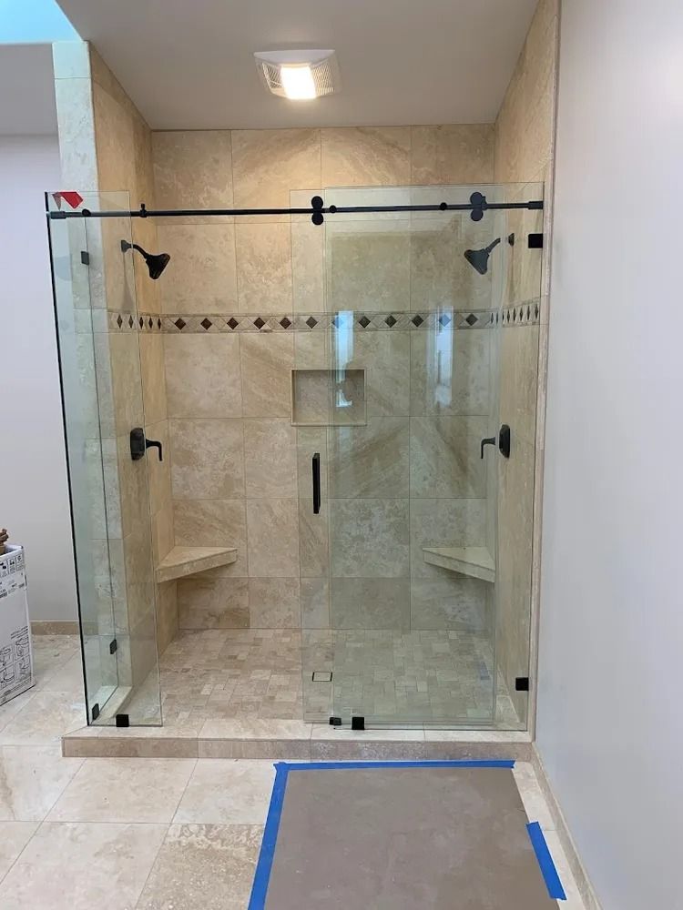 Glass-enclosed beige tile shower with sliding door and built-in corner shelves.