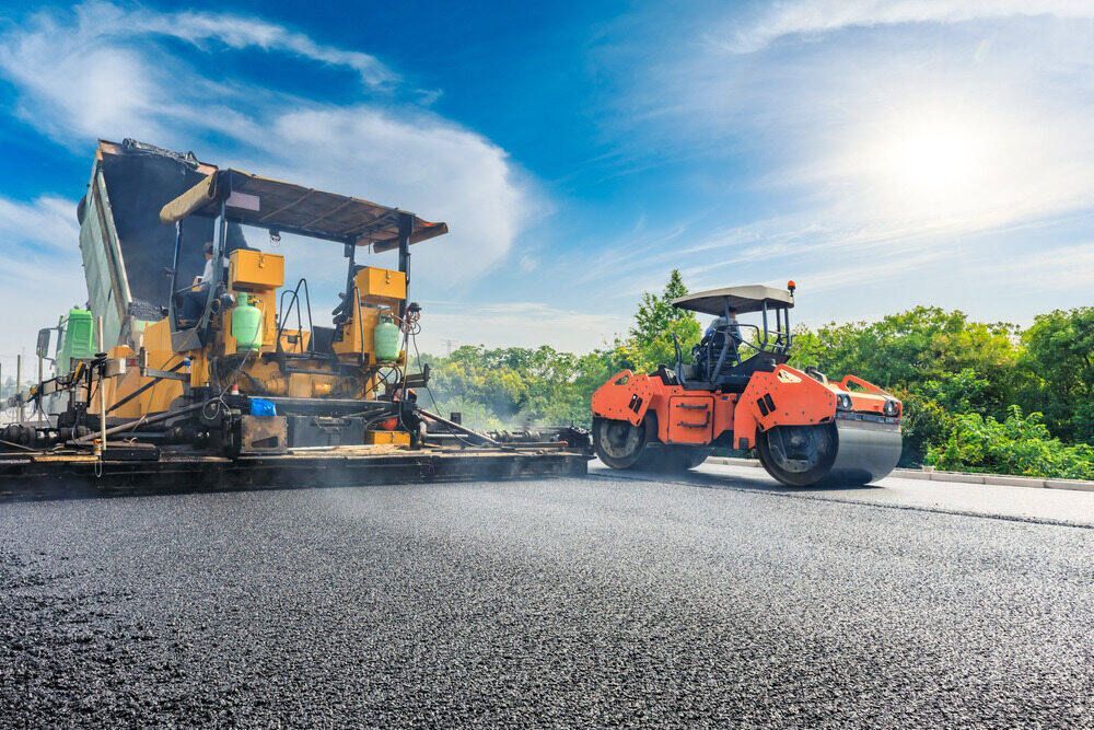 A Road Is Being Paved With A Roller And A Spreader — Appian Roads In Urangan, QLD
