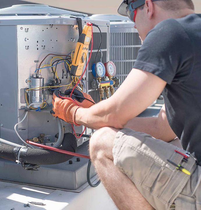 HVAC technician working on controls of air conditioner