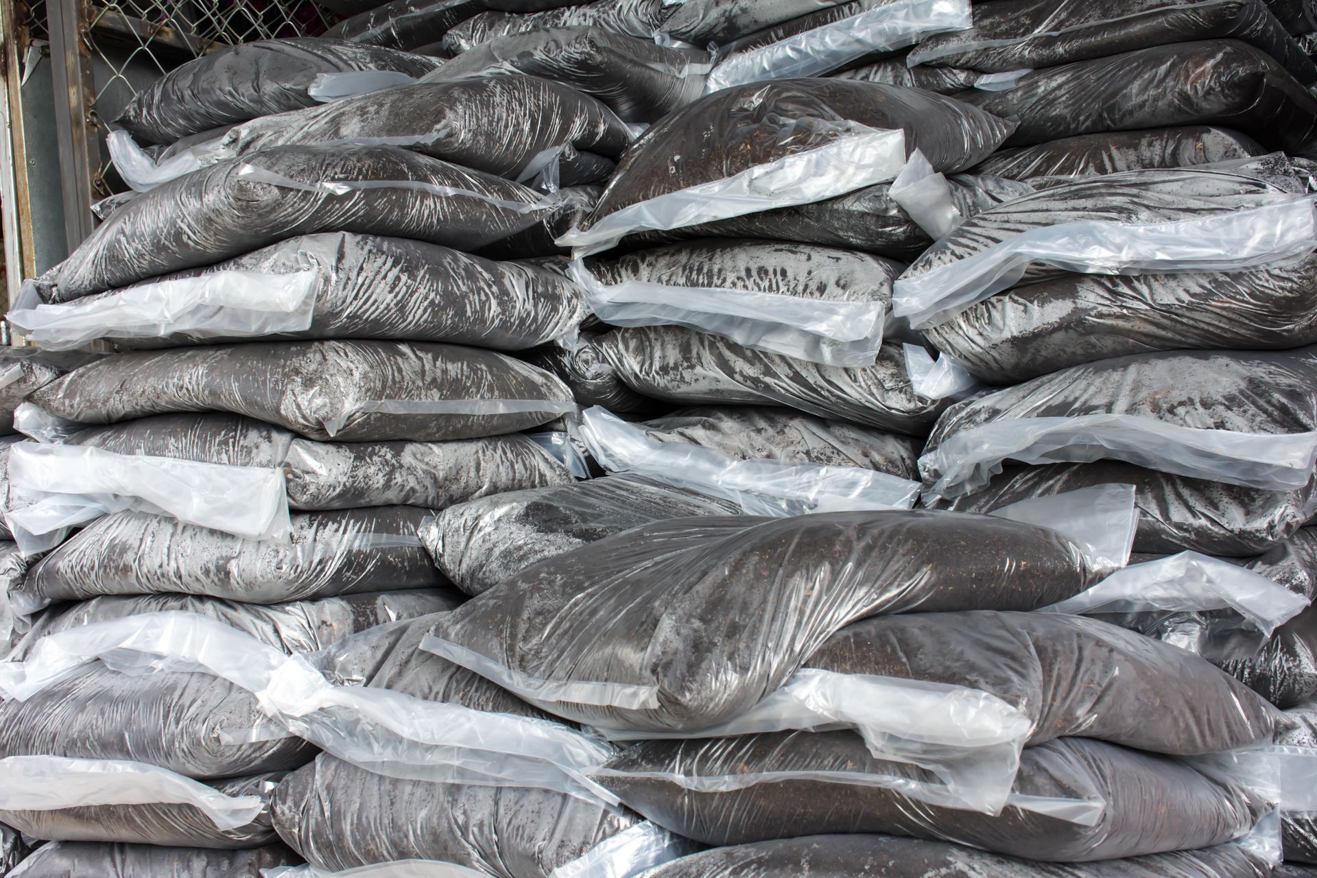 A pile of bags of dirt wrapped in plastic sitting on top of each other.