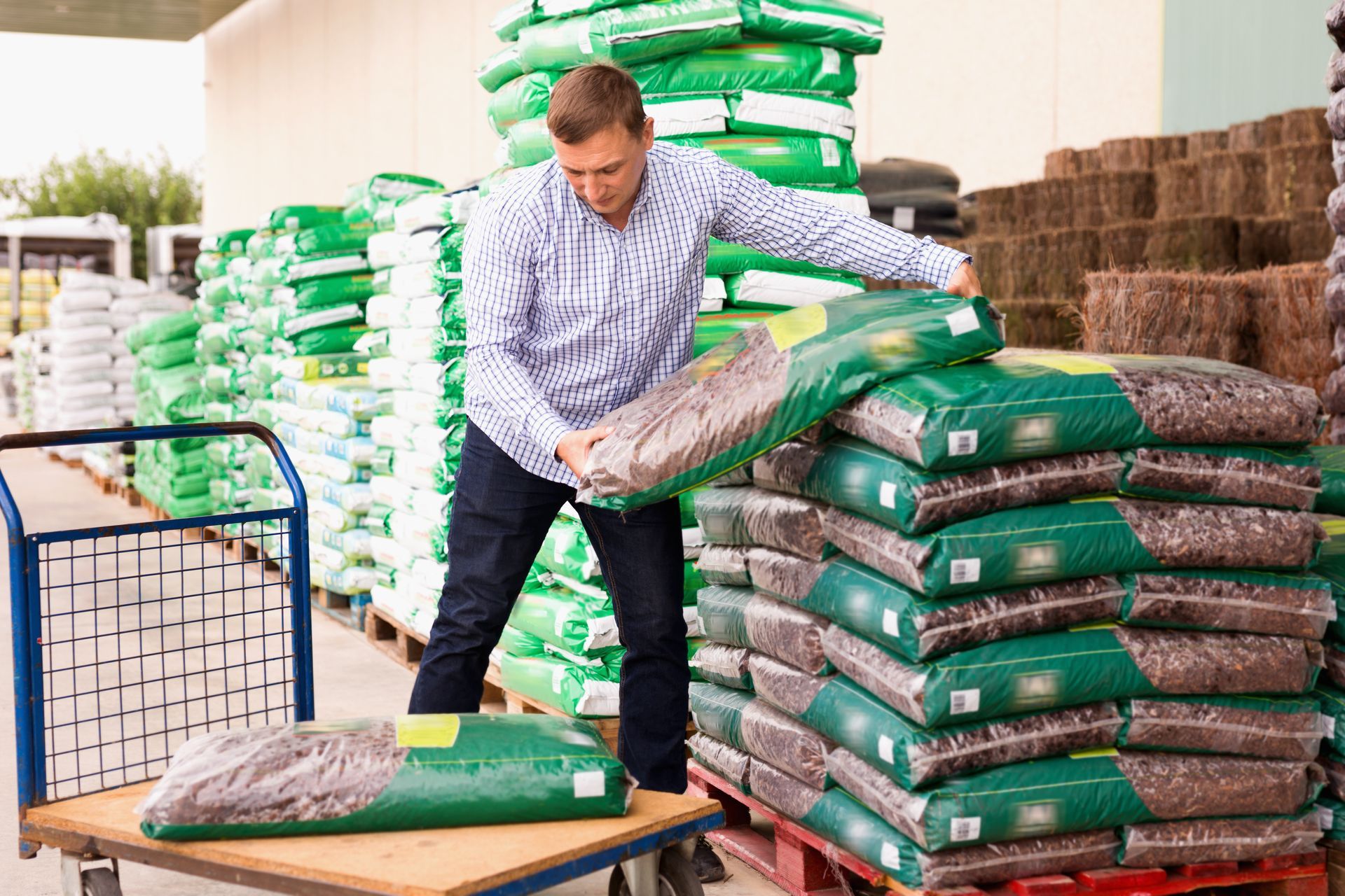 A man is loading bags onto a cart in a store.