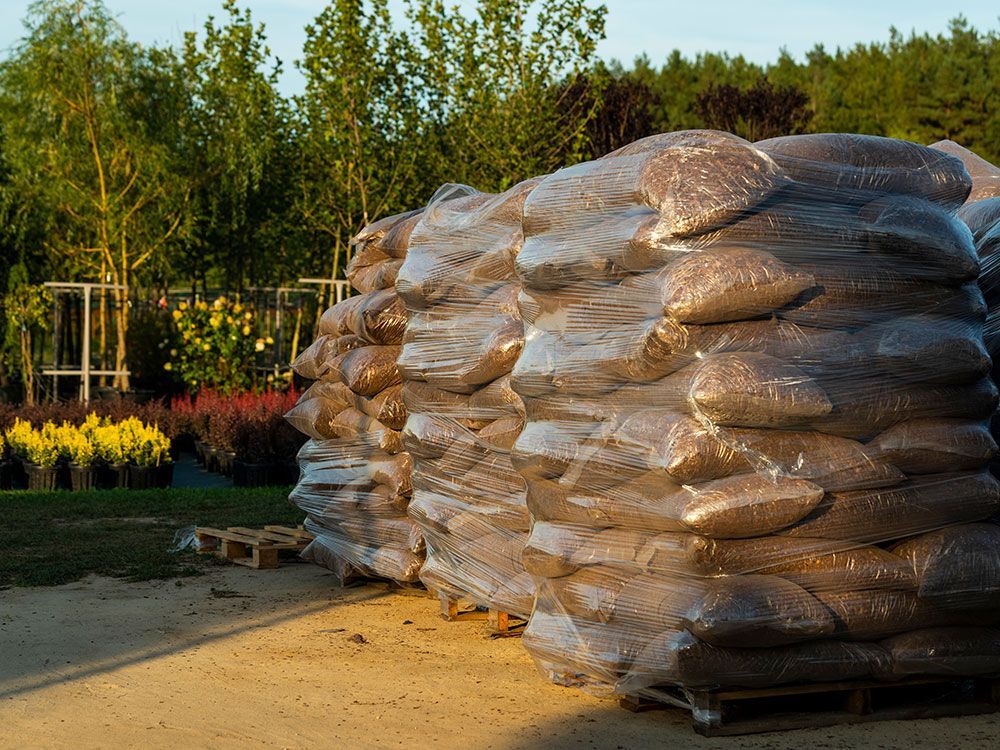 A pile of bags sitting on top of pallets in a garden.