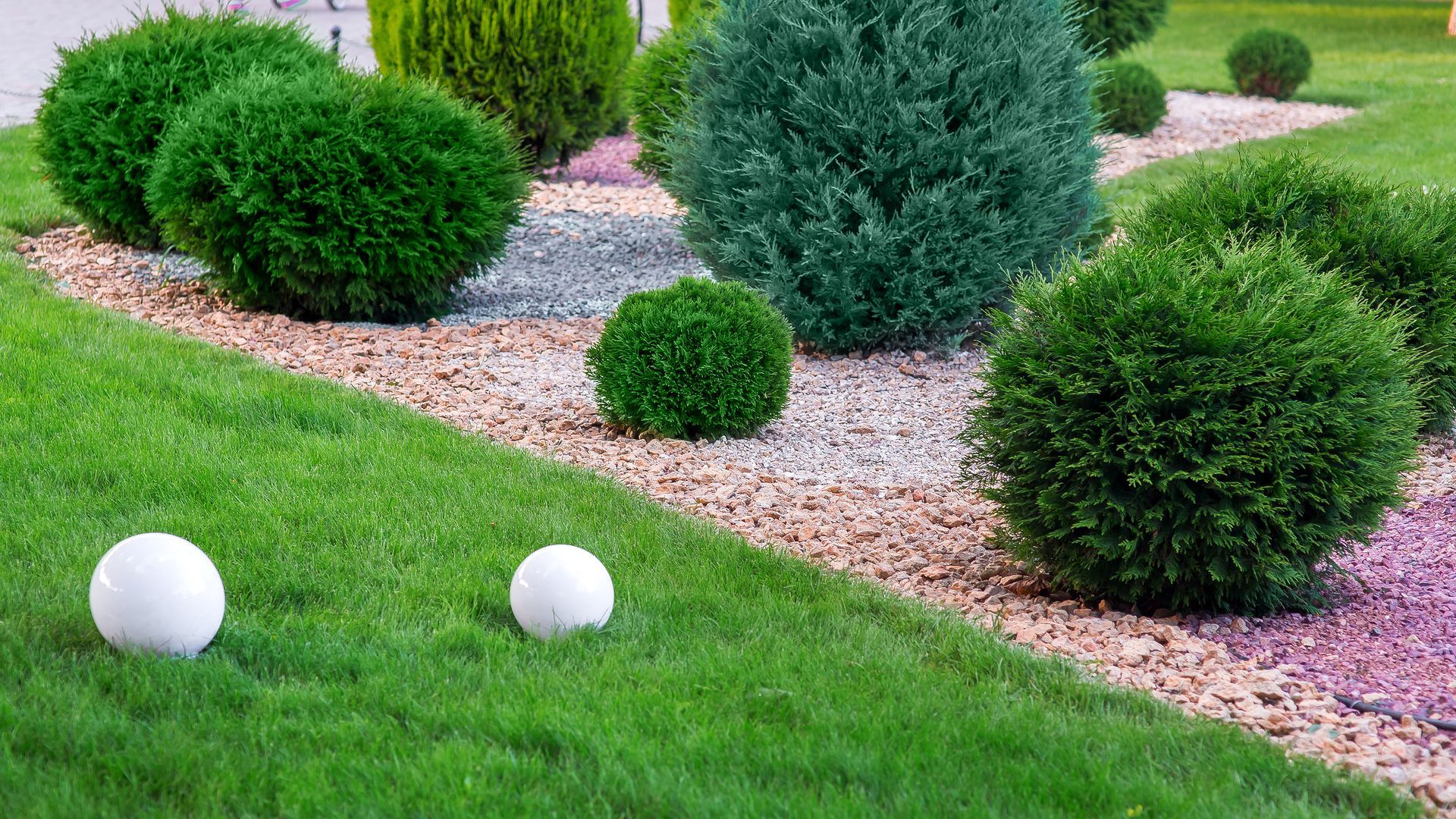 Two white balls are sitting on top of a lush green lawn in a garden.