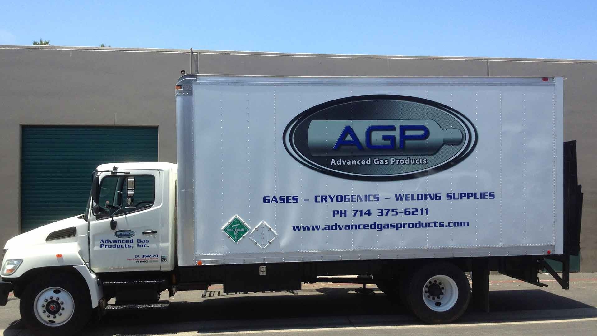A white AGP delivery truck for industrial gases and welding supplies parked in front of a building.