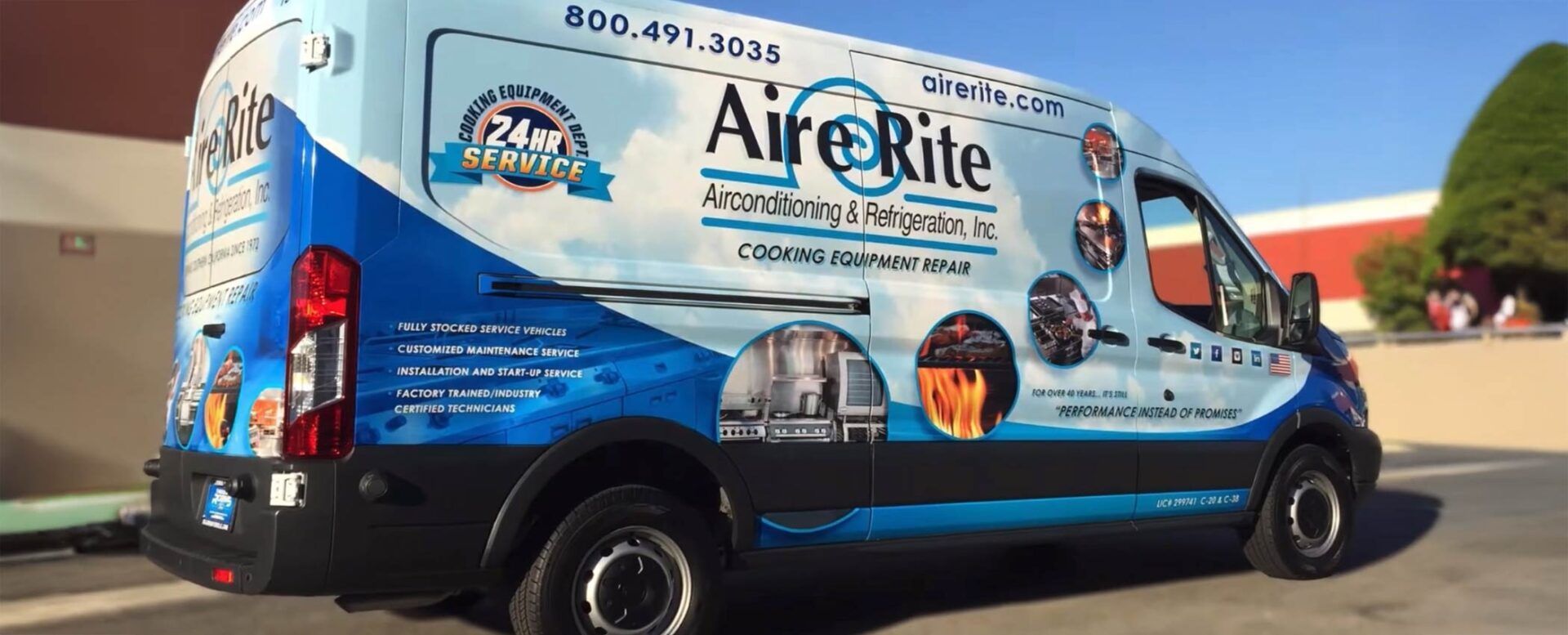 A white work van with blue graphics parked outdoors, displaying the