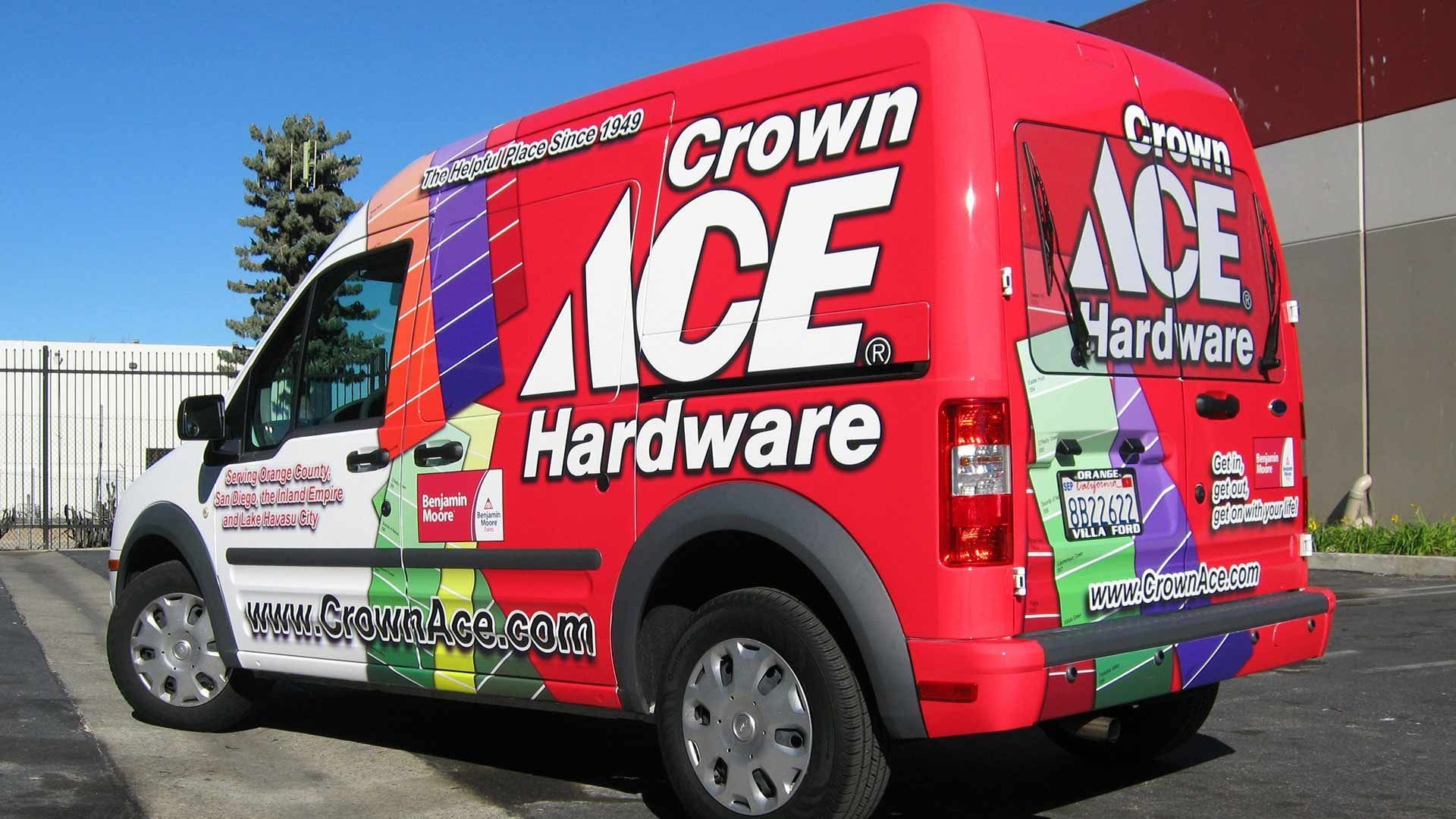 A bright red Crown Ace Hardware delivery van parked outside on a sunny day.