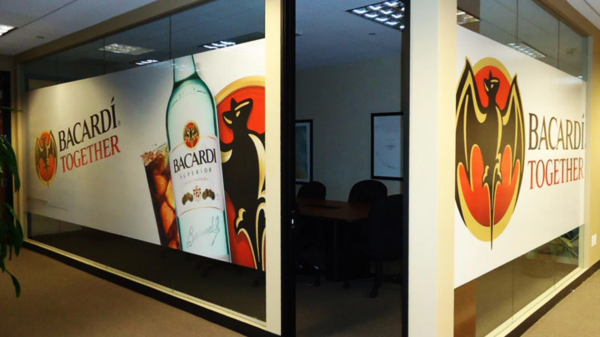 Glass office walls with Bacardi branding, featuring the logo, a rum bottle, and the phrase 