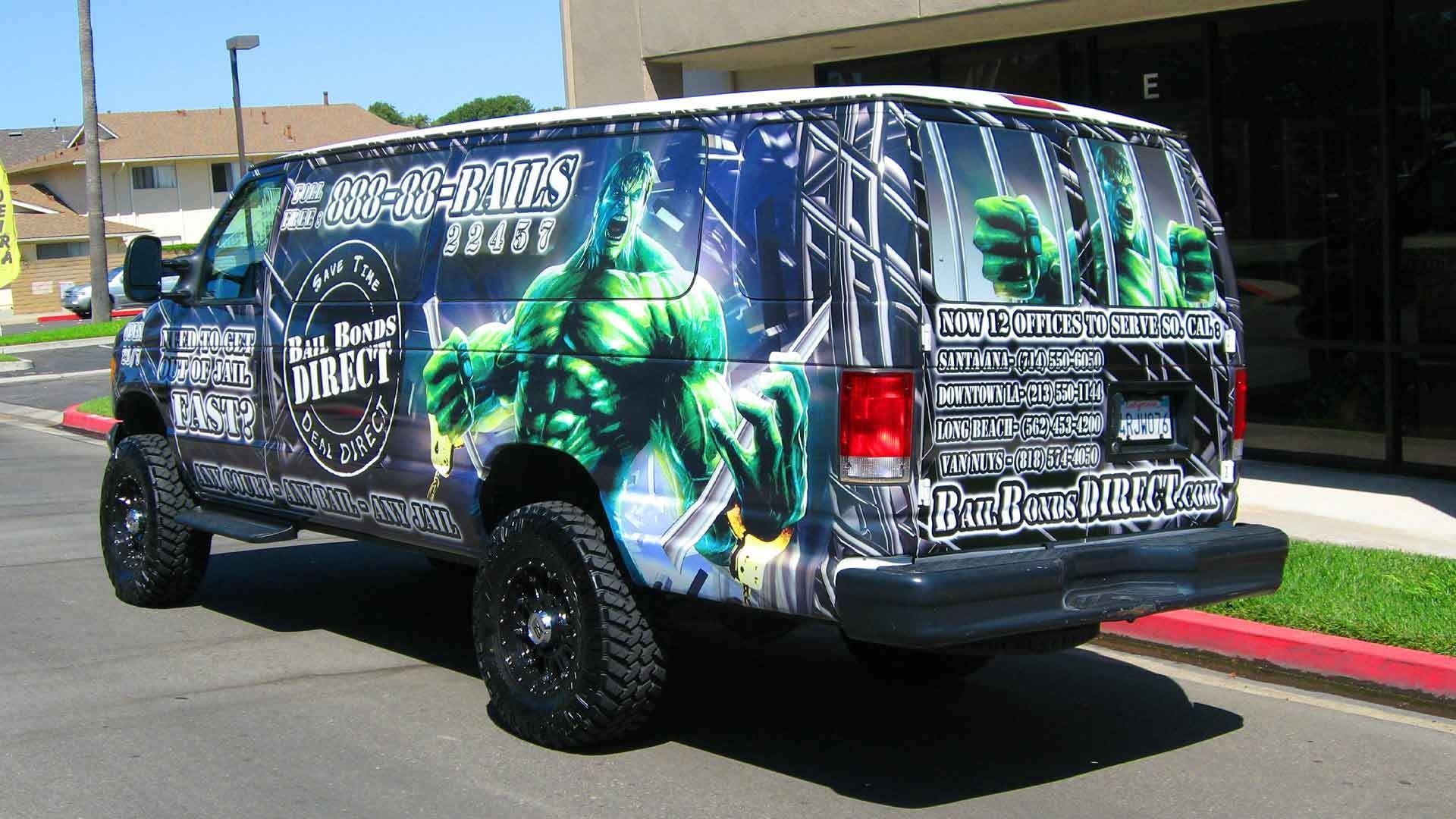 A van parked in a lot, wrapped in a large graphic of the Hulk with 