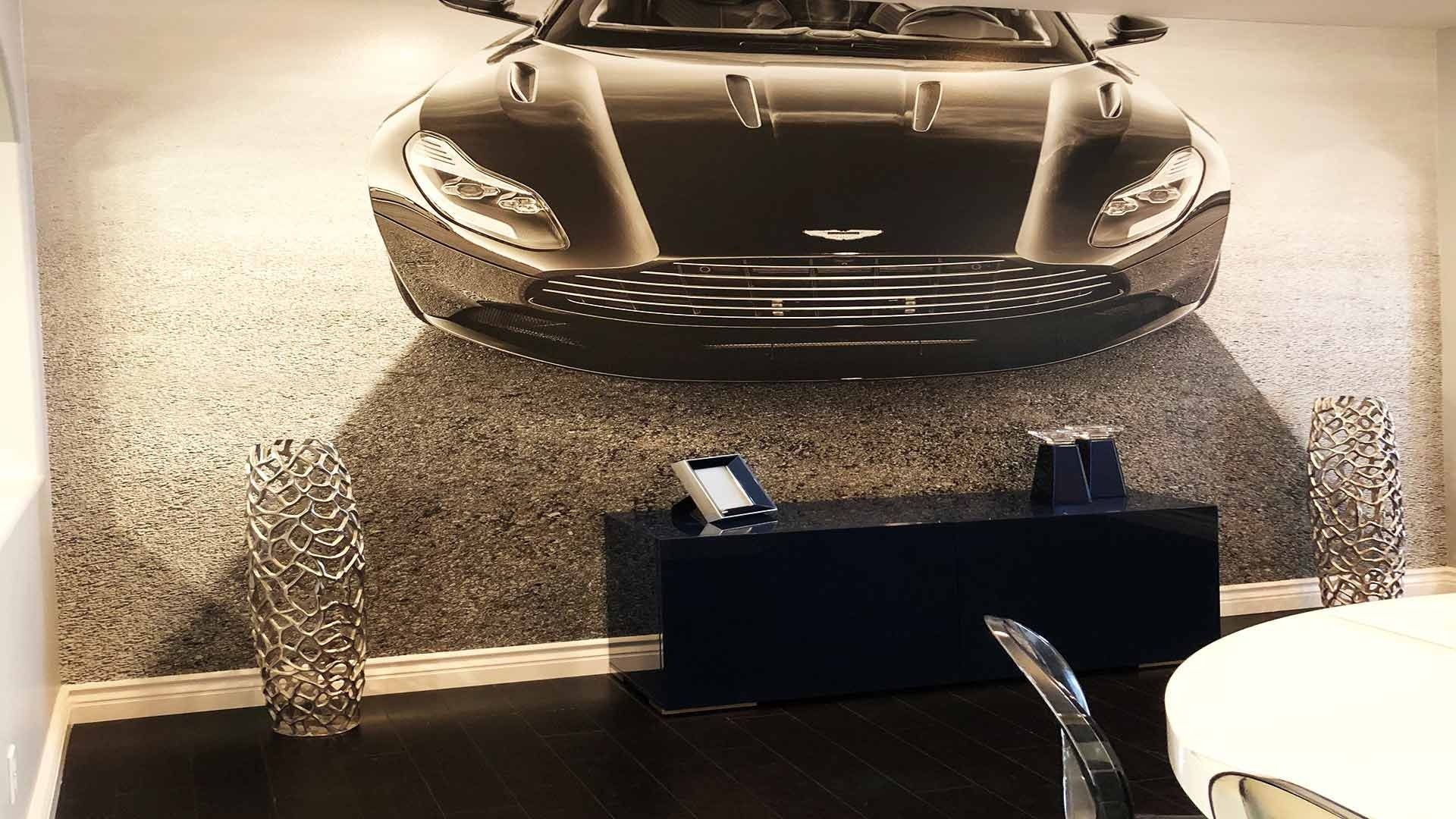 A modern room wall features a large mural of a sleek black sports car over a gray, textured gradient.