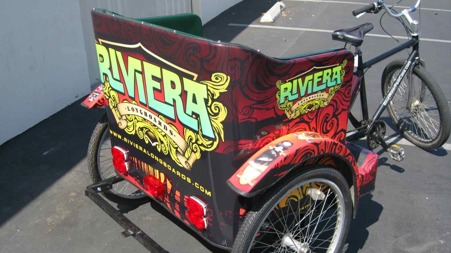 A black bicycle pedicab with red and black patterned panels and 
