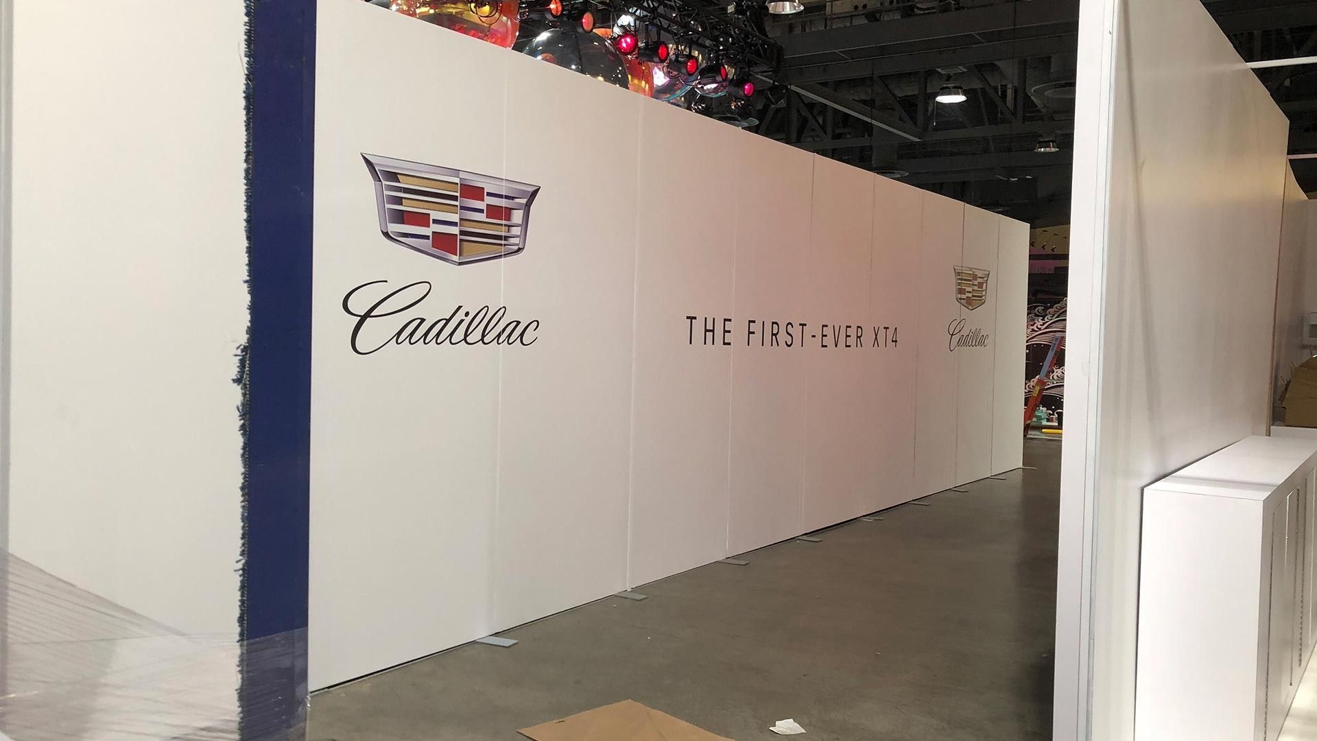 A white wall in an event space displays the Cadillac logo and the text 