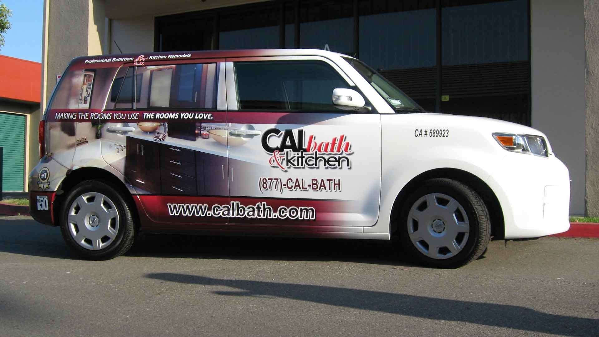 A white Scion xB parked outside a building, wrapped with advertising for 