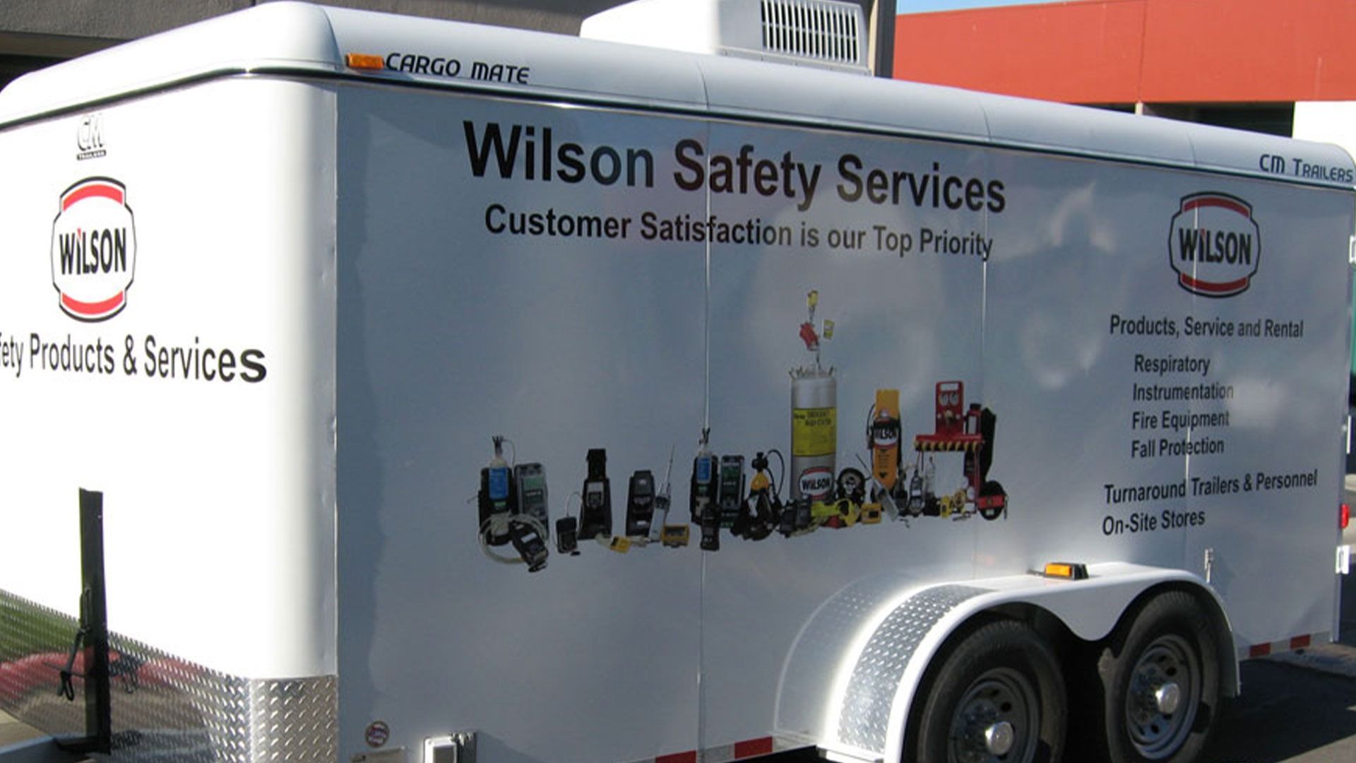 A white Wilson Safety Services trailer featuring the company logo and a display of various industrial safety equipment.