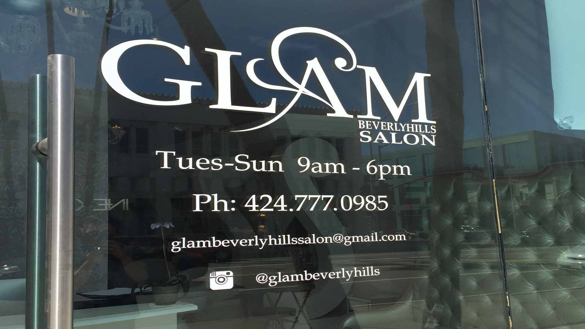 Storefront glass door for Glam Beverly Hills Salon with hours, phone number, email, and social media handle.