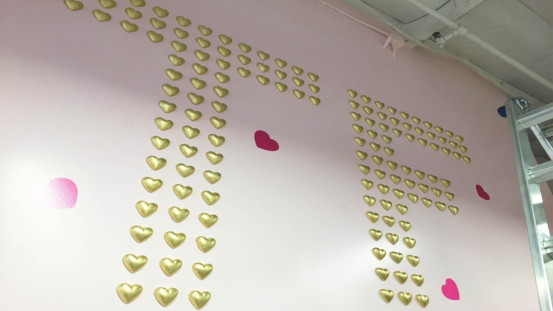 Large gold heart-shaped wall decals arranged to form the letters 